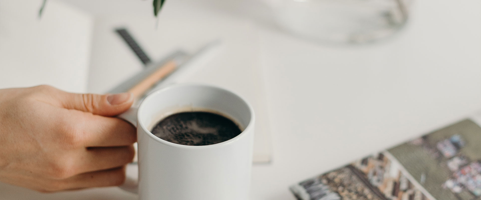 Hand hält einen Kaffee