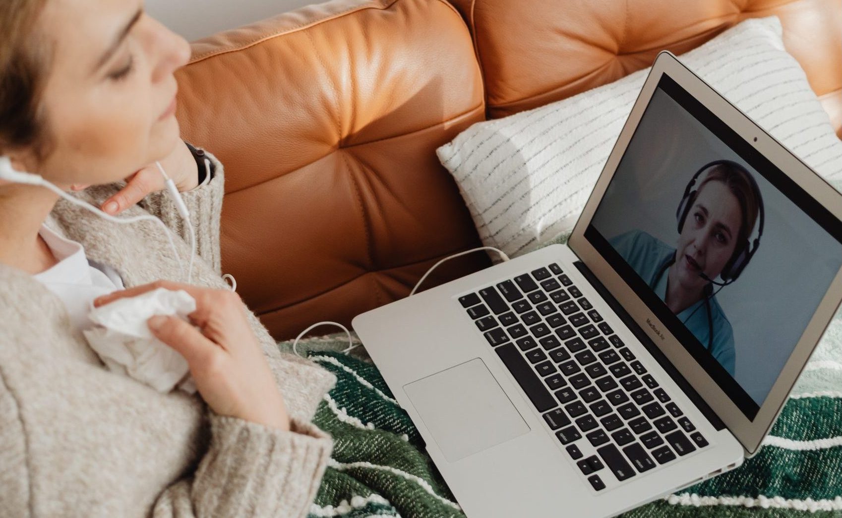 Frau mit Laptop auf dem Schoß auf der Couch