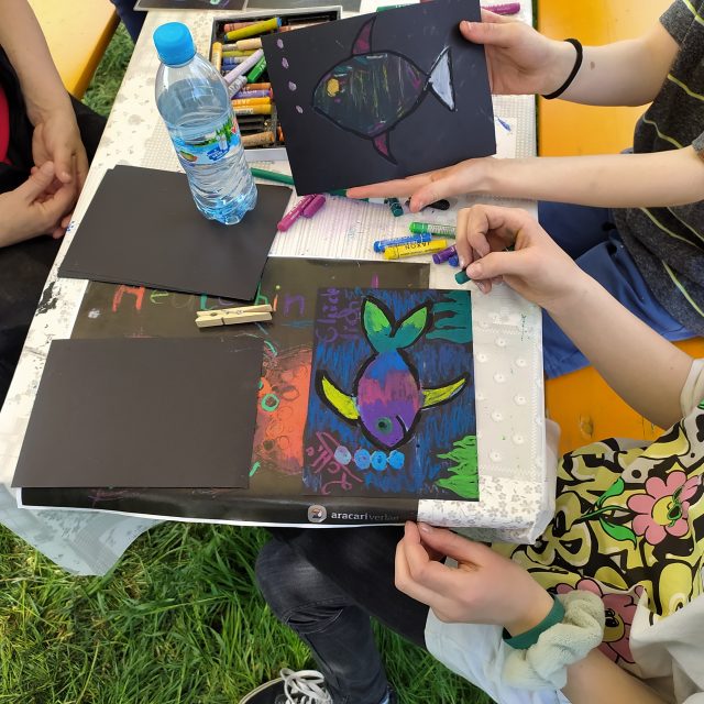 zwei Kinder zeigen ihre gemalten Fische mit Wachsmalkreide und dem dargestelltem Gefühl.