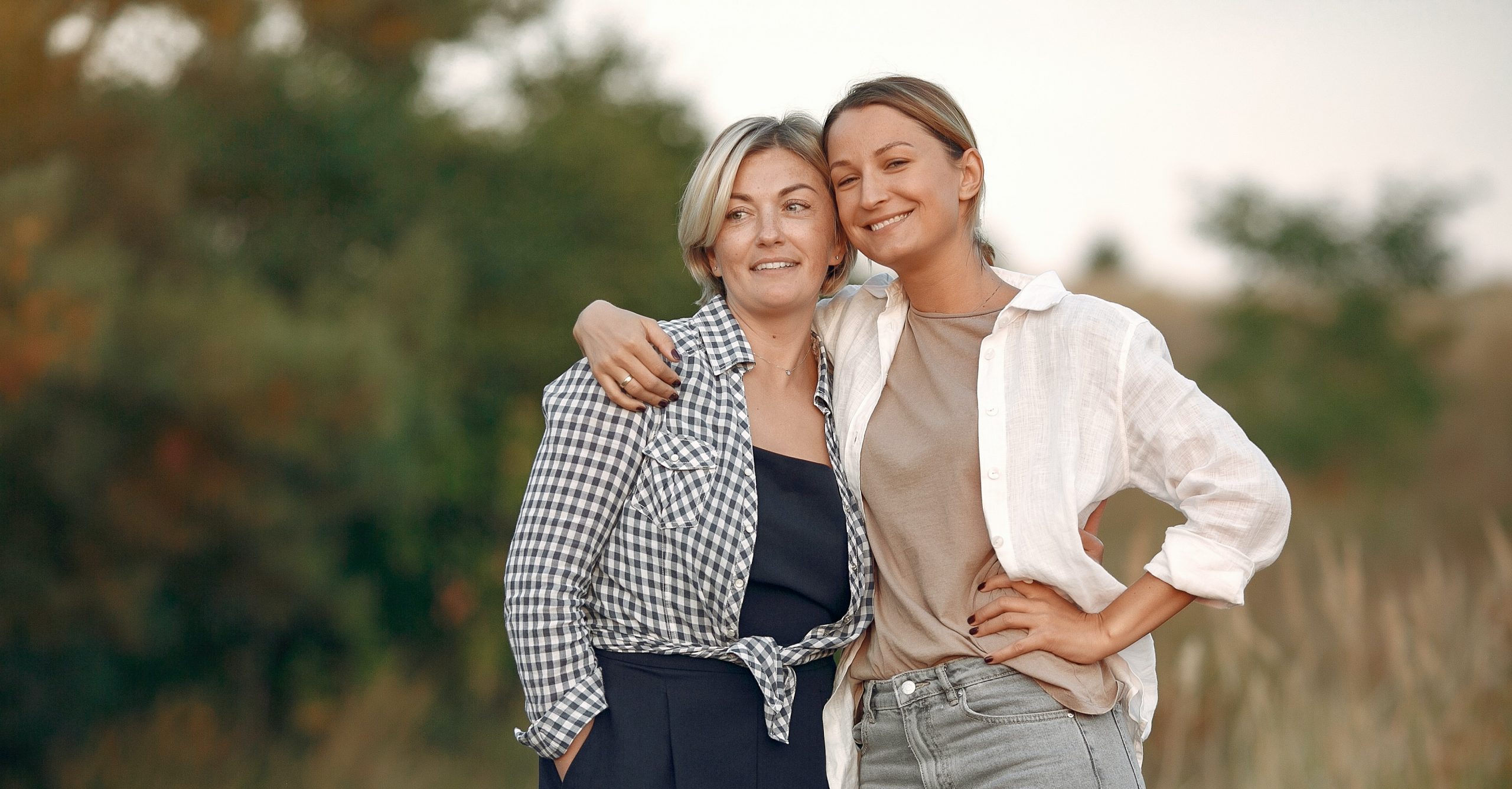 zwei Frauen halten sich im Arm, die eine ist jünger, die andere älter, beide haben ein Lächeln im Gesicht.